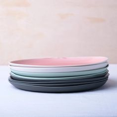 four plates stacked on top of each other with one pink plate in front of them