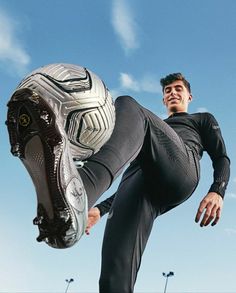 a man is jumping in the air with a soccer ball on his foot and wearing black pants