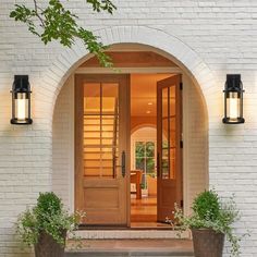 the entrance to a home with two planters on either side