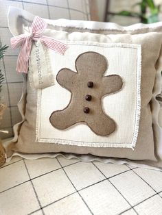 a decorative pillow with a buttoned gingerbread on the front, and a ribbon around the back