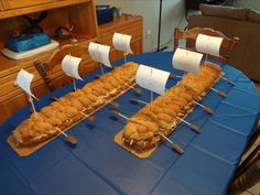 there is a table that has some food on it and two boats made out of doughnuts