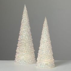 two small white christmas trees sitting next to each other