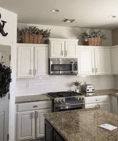 a kitchen with white cabinets and granite counter tops in front of a stove top oven