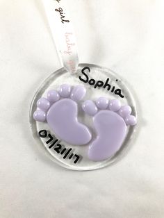 a glass ornament with two baby feet and the words saphia on it