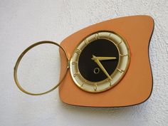 an orange and black clock on the side of a wall with a keychain attached to it