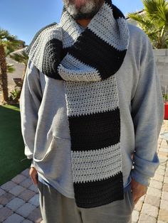 an older man wearing a black and white striped crochet scarf with his hands on his hips