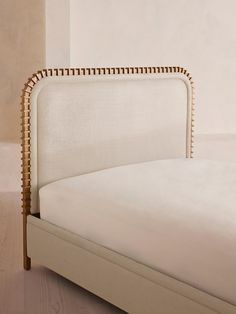 an upholstered bed with white linen and gold nailing