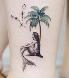 a woman sitting under a palm tree tattoo on her lower leg with stars and moon in the background