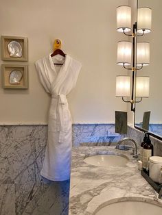 a robe hanging on the wall in a bathroom next to a marble sink and mirror