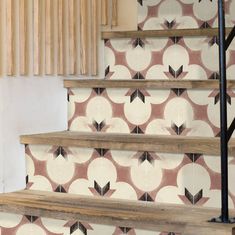 a stair case with decorative tiles on the wall and wooden handrails next to it