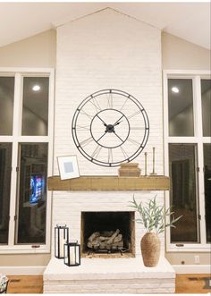 Cream floor to ceiling fireplace with natural mantle, large clock, candlesticks, on hearth is a lantern and woven vase with faux stems Wall Clock Over Fireplace Mantles, Clock Over Mantle Fireplaces, Large Clock Above Fireplace, Fireplace With Clock Above, Fireplace Mantle Decor With Clock, Clocks Over Fireplace Mantles