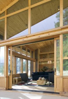 a large open living room with wood paneling and glass doors leading to the outside