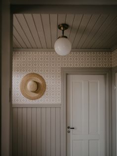 a hat is hanging on the wall next to a door with a light above it