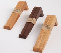 three wooden pegs with labels on them sitting next to each other in front of a white background