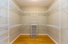 an empty walk in closet with white shelving