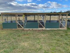 an outdoor shelter with metal steps and windows on the side in a grassy field under a cloudy blue sky