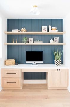 a desk with a computer on top of it in front of a blue painted wall