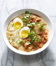 two eggs are on top of rice in a white bowl with garnishes