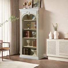 a white bookcase with books on it in a living room