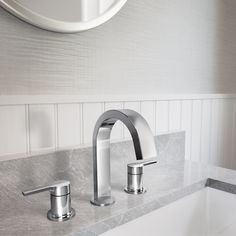 two chrome faucets sit on a marble countertop in a bathroom with white walls