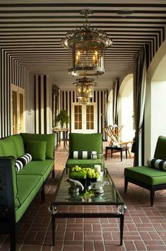 a living room with green couches and black and white stripes on the wall behind them