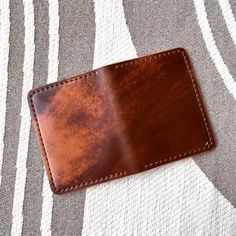 a brown leather wallet sitting on top of a striped blanket