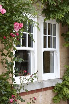 an image of a window that is on the side of a brick building with flowers growing around it