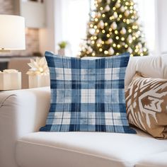 a living room with a christmas tree in the background and plaid pillows on the couch