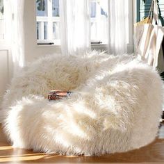 a white bean bag chair sitting on top of a wooden floor next to a window