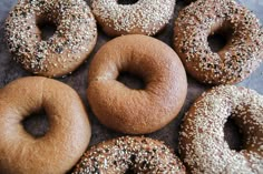 six donuts with sesame seeds and sprinkles are on the table, ready to be eaten