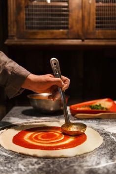 a person using a spoon to make pizza dough