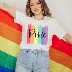 The "Pride Paint Strokes" Graphic Tee is more than just a garment; it's a vibrant celebration of diversity, love, and unity within the LGBTQ+ community. Crafted with meticulous attention to detail, this tee combines comfort with style, making it the perfect choice for expressing your pride and solidarity. The colorful rainbow paint strokes create a bold and eye-catching design, symbolizing the spectrum of identities and experiences within the LGBTQ+ community. Whether you're marching in a pride Pride Crew Neck Relaxed Fit Tops, Relaxed Fit Short Sleeve Tops For Pride, Cotton Slogan Tops For Pride Festival, Cotton Graphic Tee For Pride Festival, Trendy Crew Neck Top For Pride, Crew Neck Cotton Top For Pride, White Pre-shrunk Top For Pride, Multicolor Cotton Tops For Pride, Casual Text Print Top For Pride