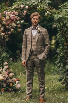 a man wearing a suit standing in front of a floral arch with flowers on it