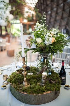 a centerpiece with flowers and candles on a table