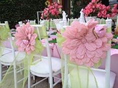 pink and green flowers are on the back of white chairs