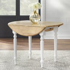 a wooden table with white flowers in a glass vase on it's end stand