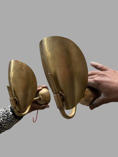 two hands are holding brass objects in front of each other