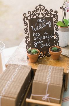 a sign that is sitting on top of some cardboard boxes and potted succulents