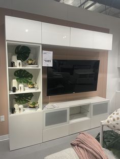 an entertainment center with white cabinets and a flat screen tv mounted on it's wall