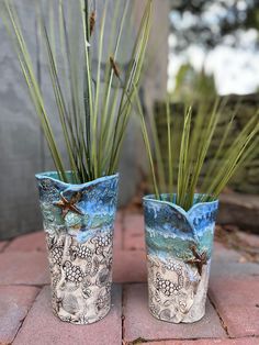 two vases with plants in them sitting on a brick floor next to each other