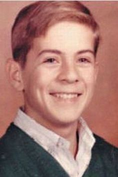 an old photo of a young man smiling at the camera and wearing a green sweater