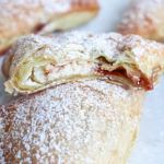 several pastries with powdered sugar on them are sitting on a white tablecloth