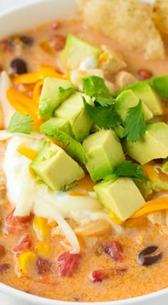 a white bowl filled with chicken tortilla soup and topped with avocado