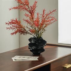 a vase filled with red flowers on top of a wooden table