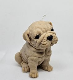 a small dog figurine sitting on a white surface with one eye open and the other half closed