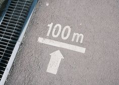 an arrow pointing to the right on a street with a grate next to it