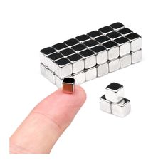 a finger is pointing at some metal cubes