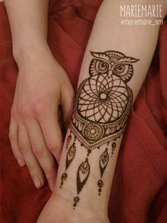 a person with a tattoo on their arm that has an owl and dream catcher on it