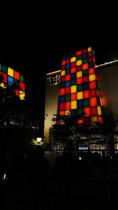 a tall building with multi colored squares on it's side and a clock tower in the background