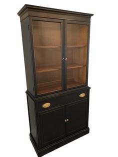 a black china cabinet with glass doors and gold trimmings on the bottom shelf